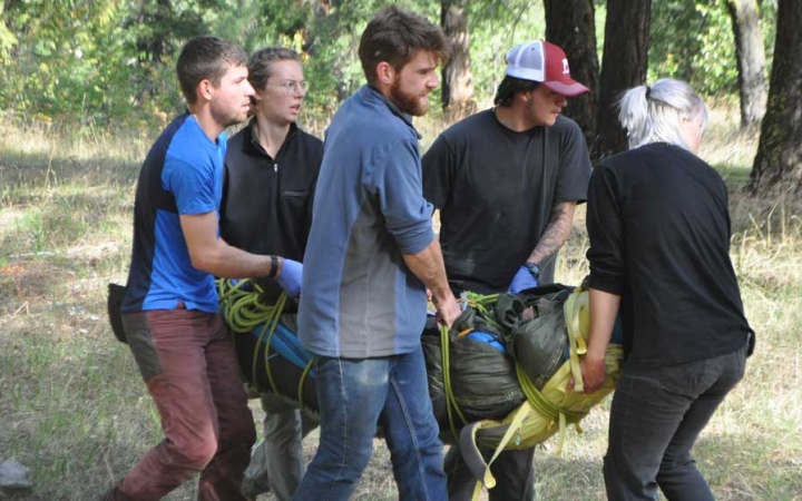 five people carry someone during a wilderness first responder course